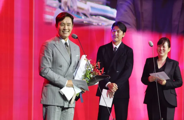 李秉憲（左起）從上屆影帝鄭雨盛手中接下獎座。翻攝釜山日報