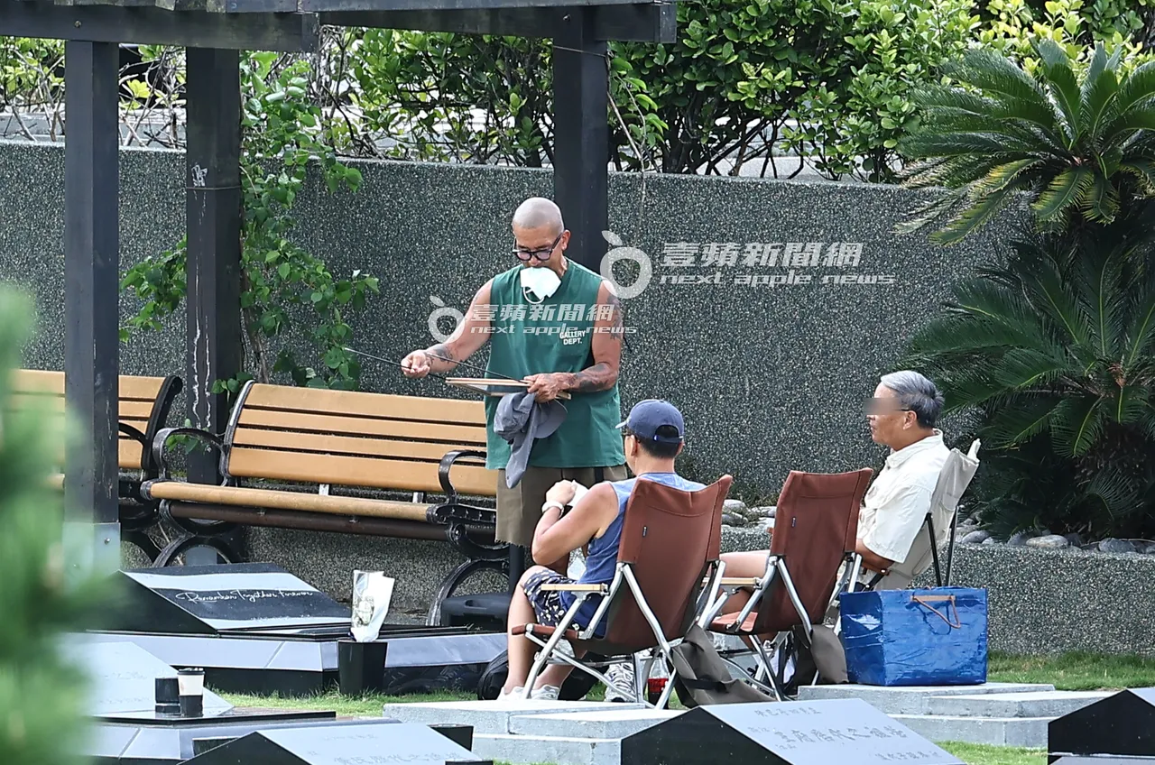 具俊晔(左)脱掉遮阳帽子叼著口罩,边将友人制作的标语牌收起。特勤中心摄