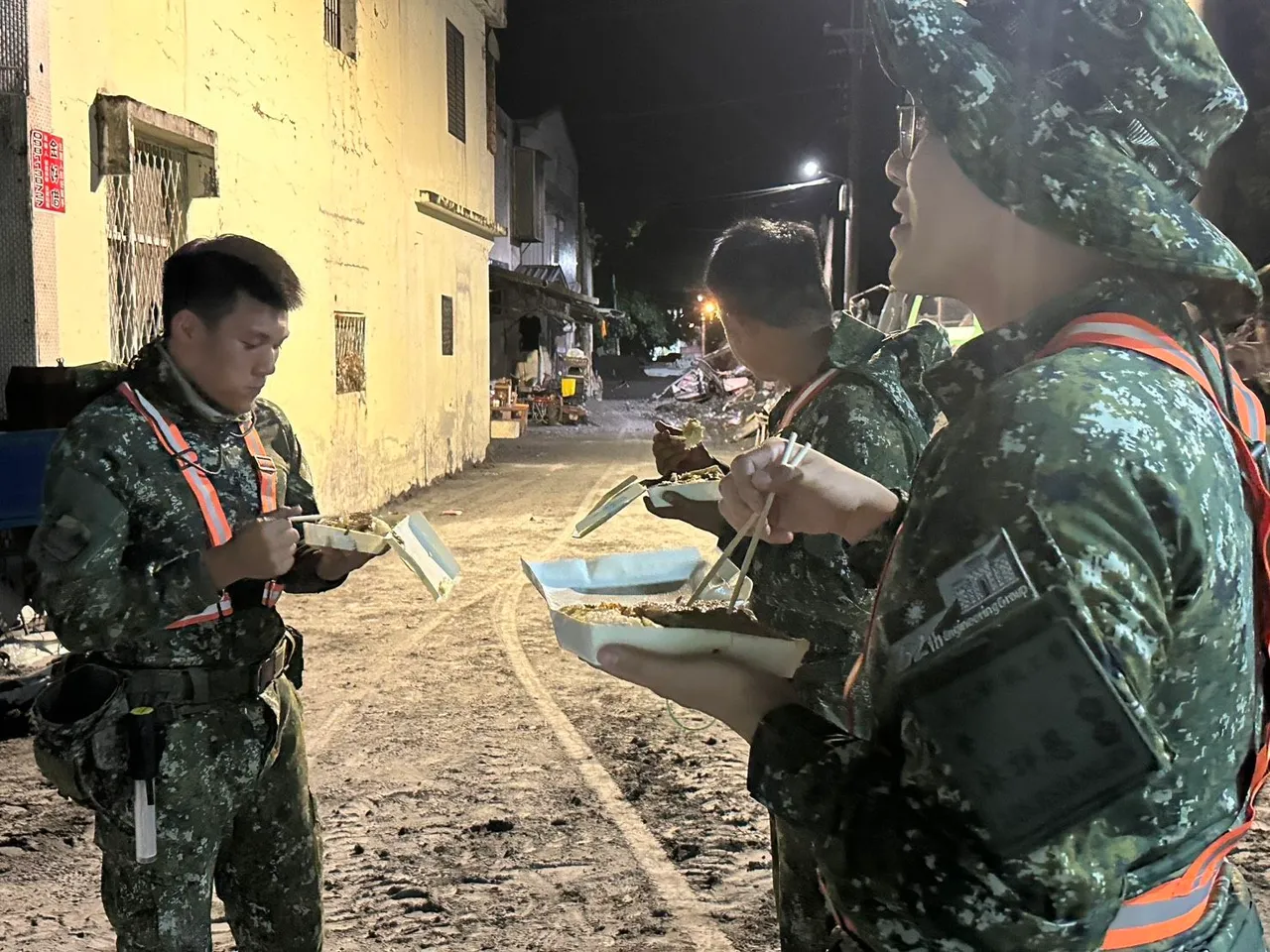 大家站在满目疮痍的光复乡街头吃便当。军方提供