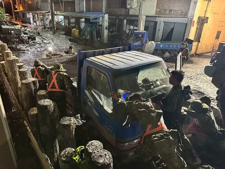 大家在爛泥堆中合力推動受災車輛。軍方提供
