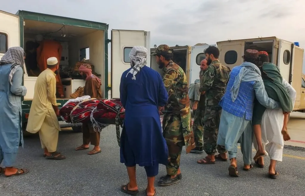 塔利班士兵和民众将地震伤者抬上救护车。路透社