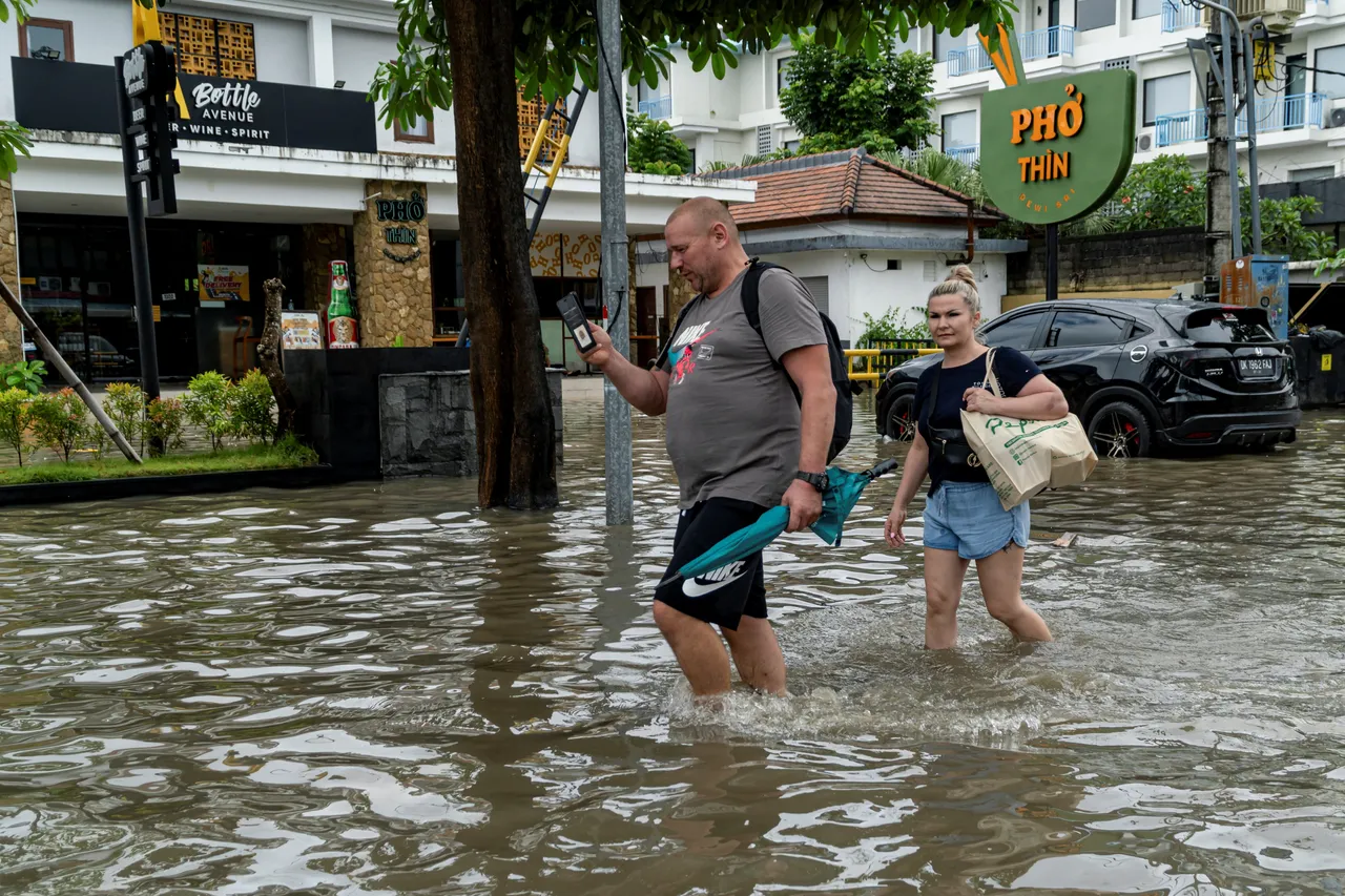 外国游客在马路上涉水行走。路透