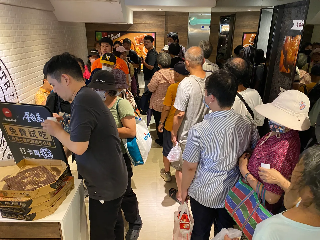 「月见七盎司厚烧牛比萨」免费试吃,现场吸引上百位民众排队。庄伟祺摄