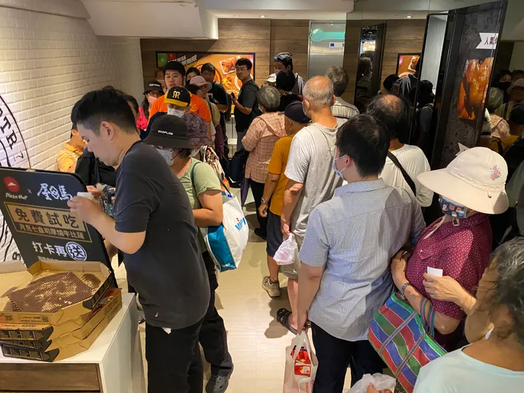 「月見七盎司厚燒牛比薩」免費試吃，現場吸引上百位民眾排隊。莊偉祺攝