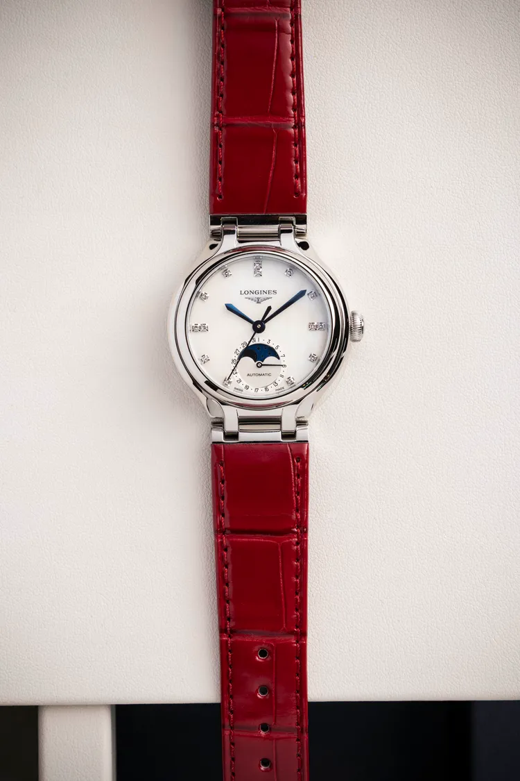 浪琴PRIMALUNA新月系列珍珠面盤腕錶，34mm，不鏽鋼錶殼，白色珍珠母貝錶盤，紅色鱷魚皮革錶帶，浪琴表獨家L899.5自動上鍊機械機芯，動力儲存72小時，防水深度30米，10萬3900元。品牌提供