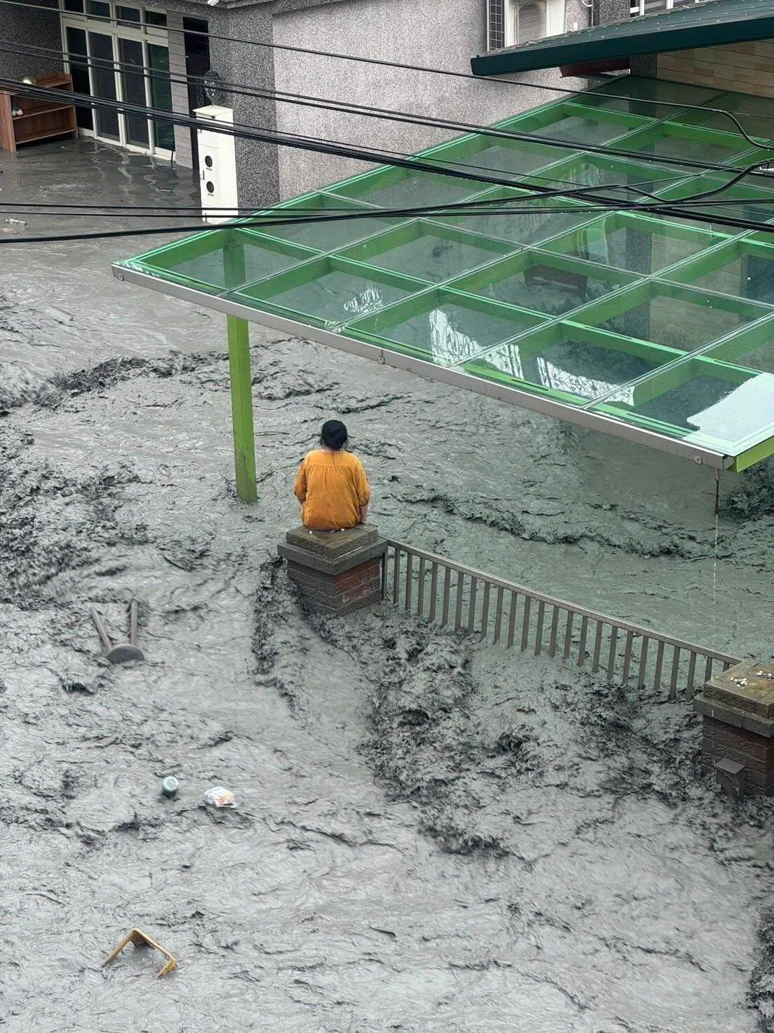 一名妇人坐在屋前柱子上待援。翻摄画面
