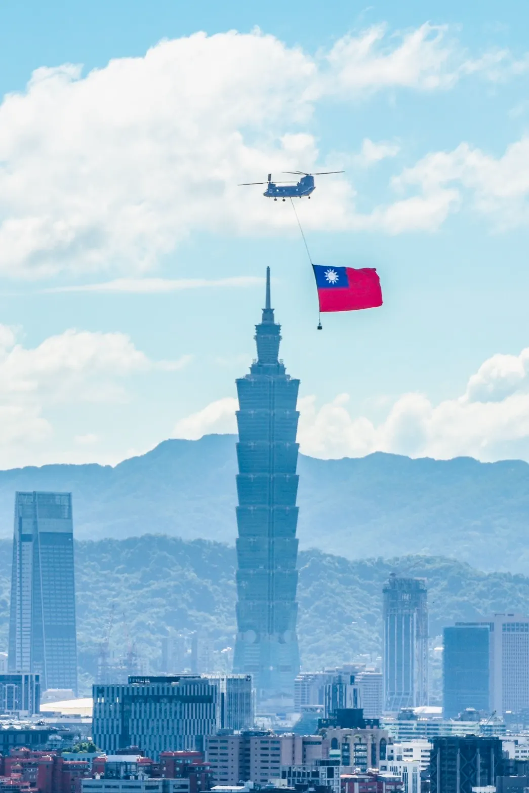 陸軍一架CH-47SD契努克重型直升機吊掛巨幅國旗,飛越台北101上空。讀者提供