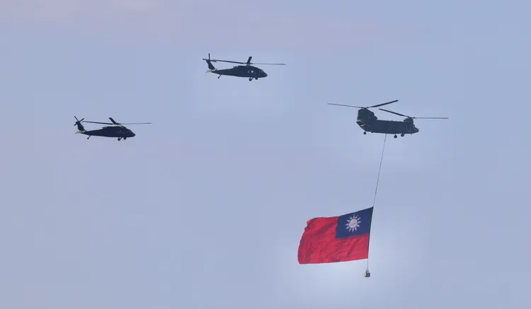 CH-47SD運輸直升機及UH-60M通用直升機2架次編隊吊掛巨幅國旗通過總統府前方，壯觀畫面吸引民眾駐足觀賞。莊宗達攝