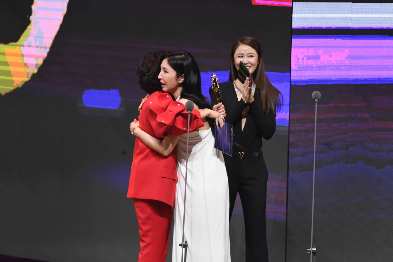 杨谨华(白色裙装者)与颁奖者杨贵媚拥抱。三立提供