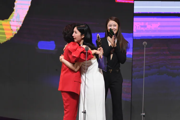 楊謹華（白色裙裝者）與頒獎者楊貴媚擁抱。三立提供
