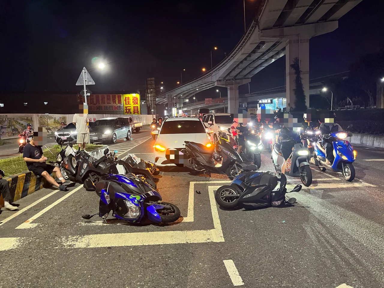 宾士车撞进待转区,5辆机车东倒西歪,受伤机车骑士无奈坐在一旁等待救援。翻摄画面