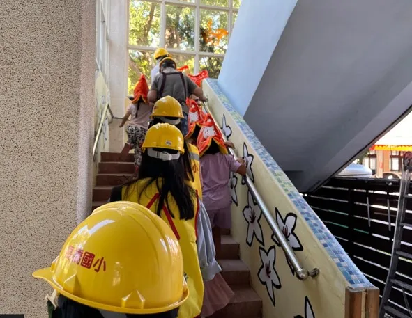 小朋友頭戴安全帽前往高處避難。縣府提供