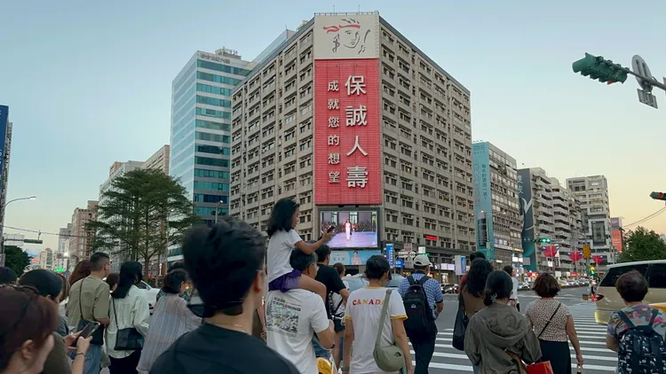 印象廣告直播夏姿巴黎時裝秀，吸引大人背著小孩圍觀。陳建岐攝