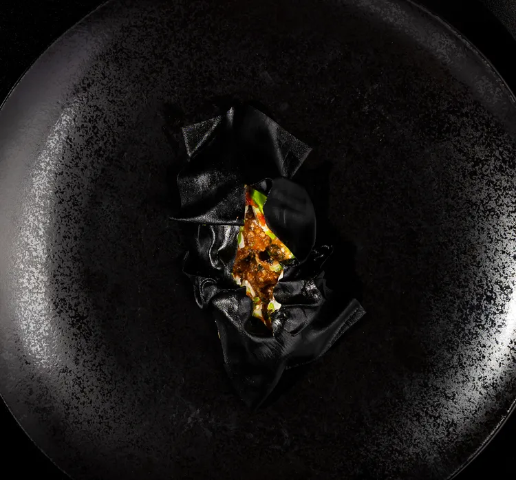 「Sine by Di Pinto」羅伯托主廚義式創意饗宴，「炸茄子起司球」以墨黑的低調奢華風格呈現，脆皮泡芙外皮中內蘊紅味噌與烤白芝麻交融的帕瑪森焗烤茄子，濃郁起司的奶香與茄子的清潤相映。台北文華東方酒店提供
