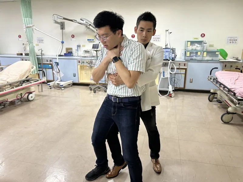 哈姆立克急救法是救护者站在病人后方,左手握拳,右手包住左拳,双手置于病人肚脐到胸骨中间往后往上推挤。卫福部嘉义医院提供