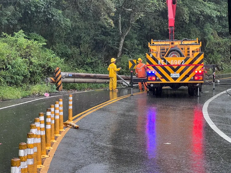 2電桿被砂石車後車斗勾斷，直接橫躺路中，台電人員與市府人員正積極搶修當中。翻攝畫面