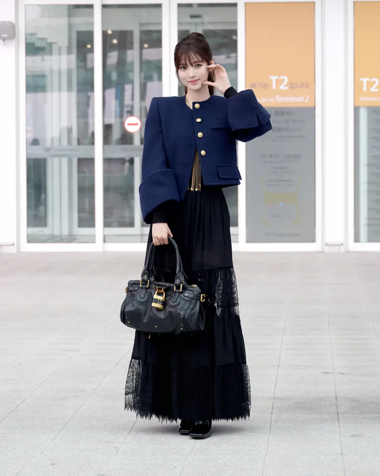 Anna身穿黑色透膚蕾絲絲質上衣、長裙，搭配深藍色格紋短夾克。品牌提供