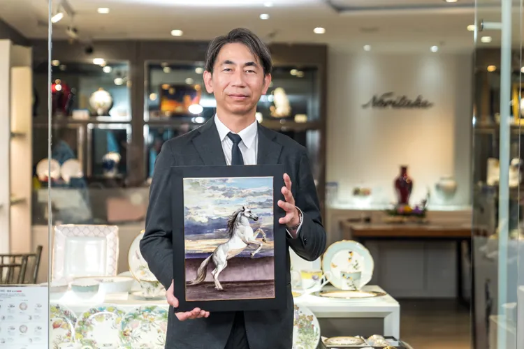 日本手繪職人岡田正己手持代表作〈駿馬奔騰〉，以奔放筆觸描繪馬匹躍動神韻，象徵力量與勇氣的藝術意象。圖/ 旺代企業提供