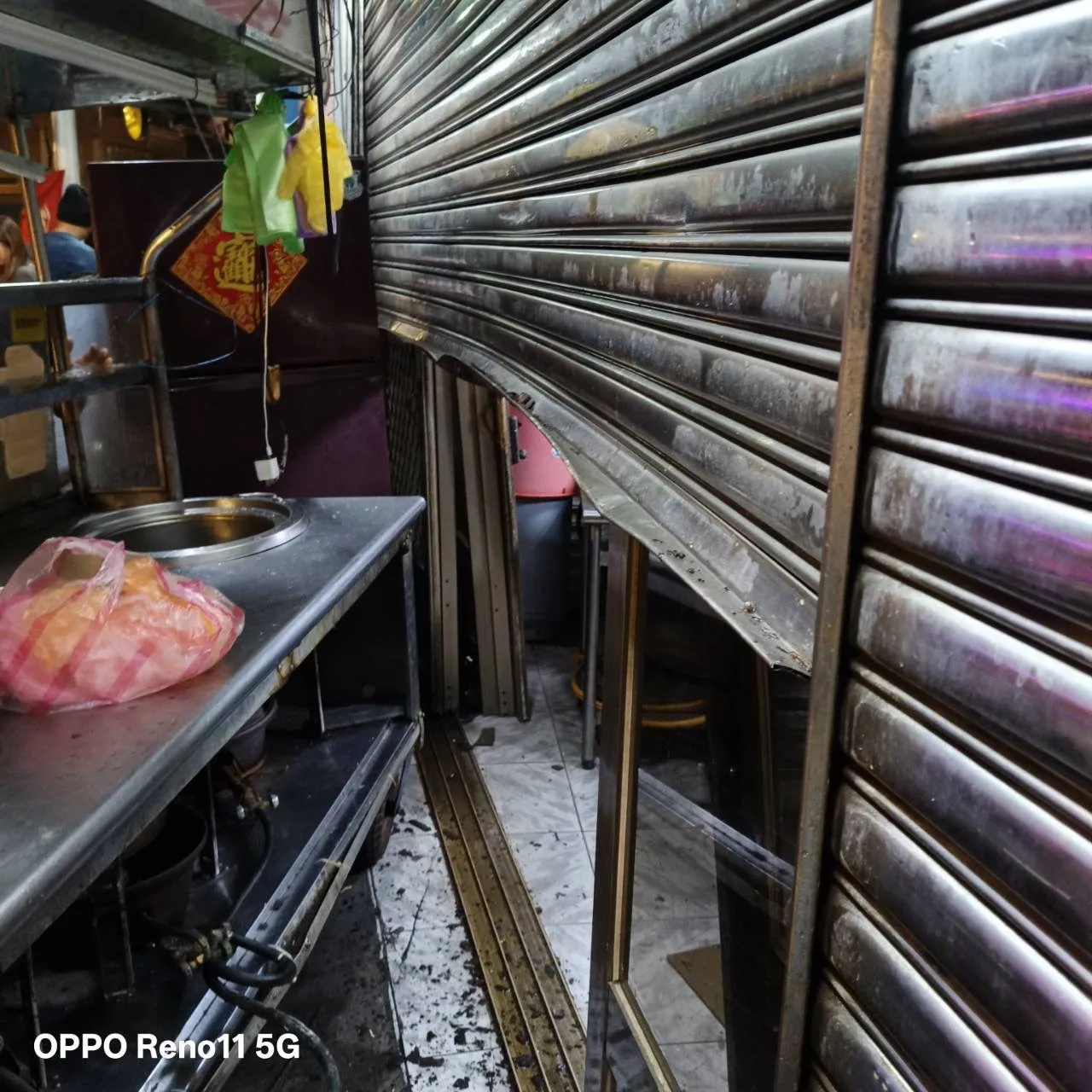 路边小吃摊位被推挤移位,将后方店面铁卷门撞到变形。翻摄画面