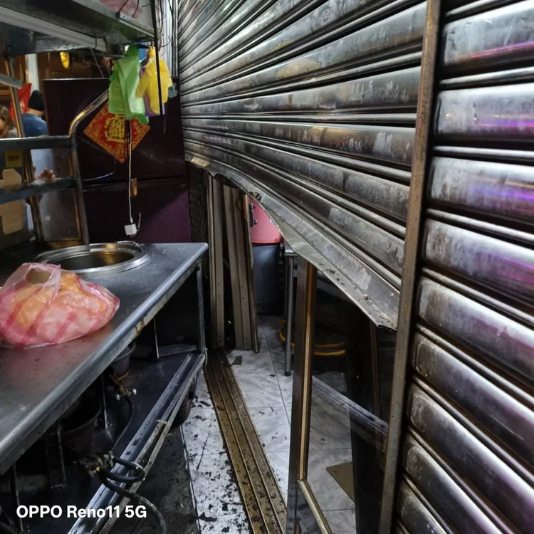 路邊小吃攤位被推擠移位，將後方店面鐵捲門撞到變形。翻攝畫面