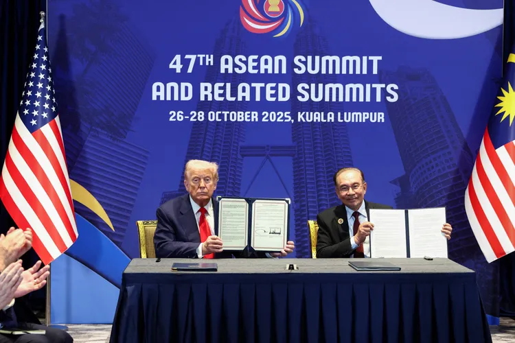 美国总统川普(左)与马来西亚总理安华于第47届东南亚国家联盟(ASEAN)高峰会期间在马来西亚吉隆坡举行双边会晤时,举起贸易协定文件合影。路透