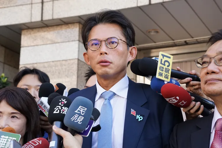 民眾黨主席黃國昌身著深藍西裝、淺藍領帶，左胸前佩戴國旗與代表柯文哲的KP徽章。邱筠媜攝