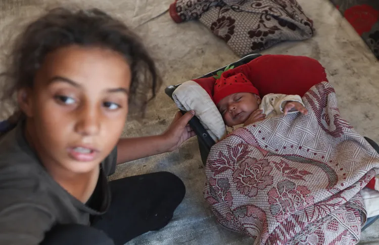 難民小姊姊還要幫忙照顧最小的弟弟。路透社