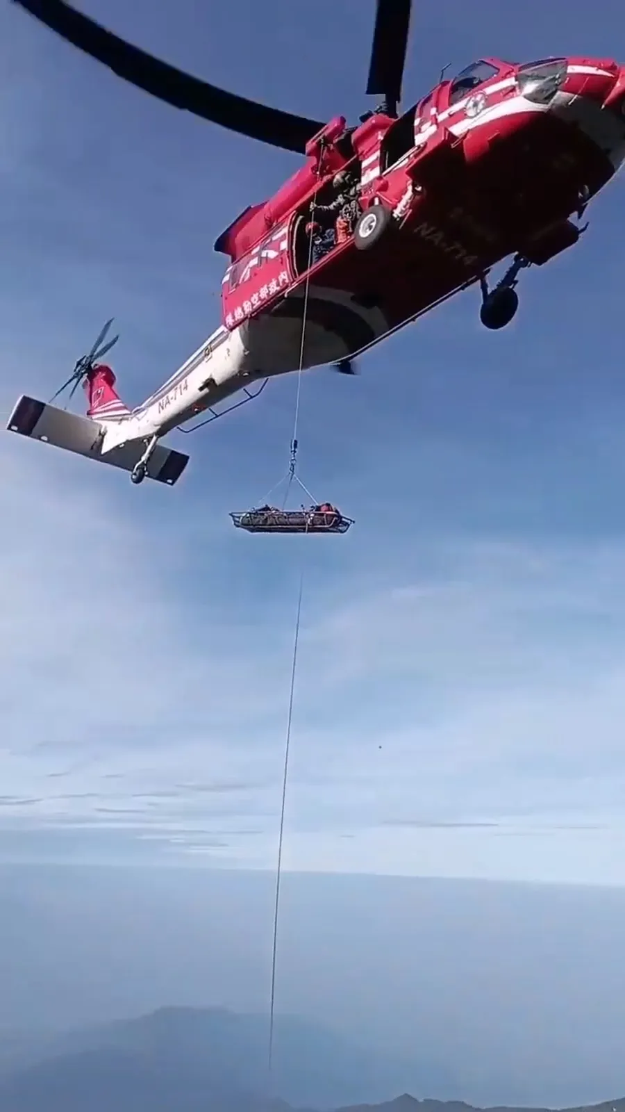 直升机将脚伤女山友吊挂救援，送到山下。翻摄画面