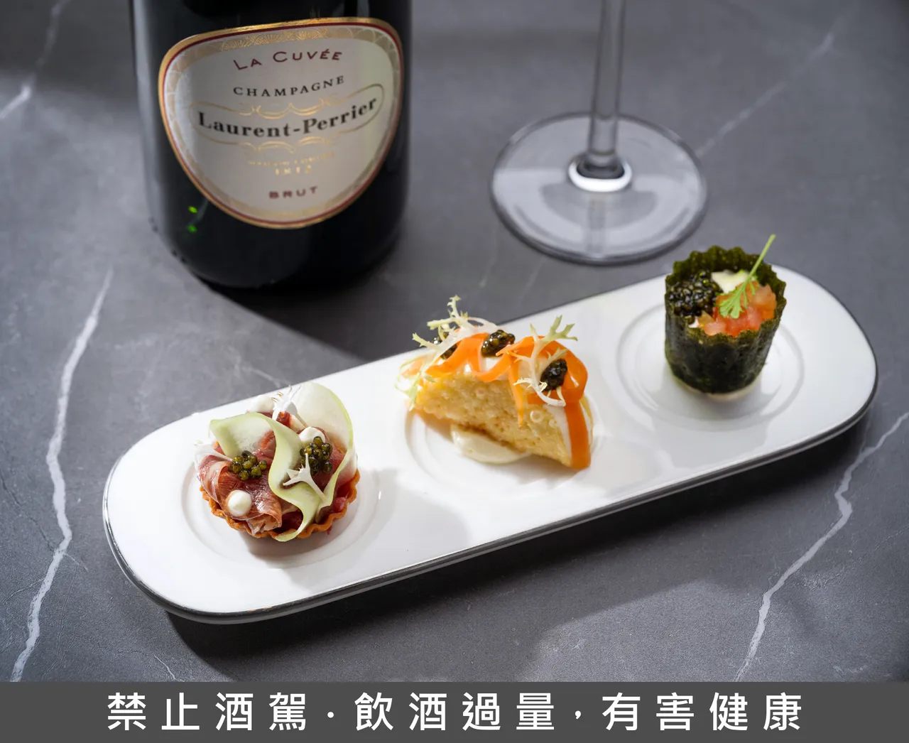 「迷你玉米餅佐鱈魚醬、醃漬蘿蔔、酸豆」、「羊肉韃靼塔、醃漬羊肉、優格、萵苣」及「海苔塔佐雞肉沙拉、蛋黃醬、番茄」，搭配「薩魯加」(Sevruga) 魚子醬，佐以餐前開胃香檳「羅蘭香檳Laurent-Perrier La Cuvée Brut, Champagne, France」。台北文華東方酒店提供