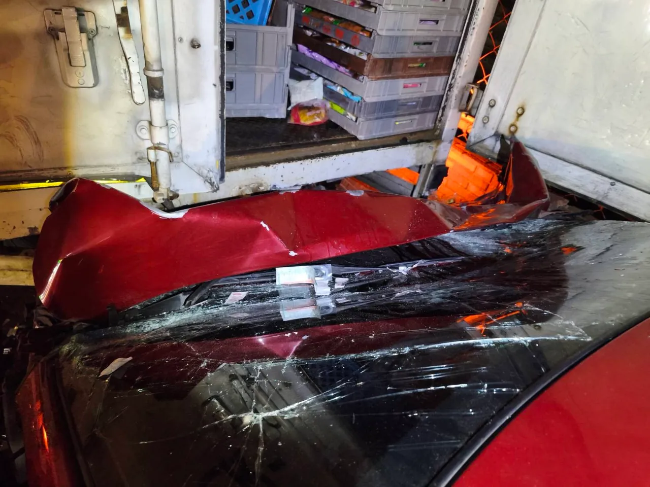 紅色轎車未減速衝入貨車後方底部，現場一片狼藉，可見撞擊力之大。翻攝畫面