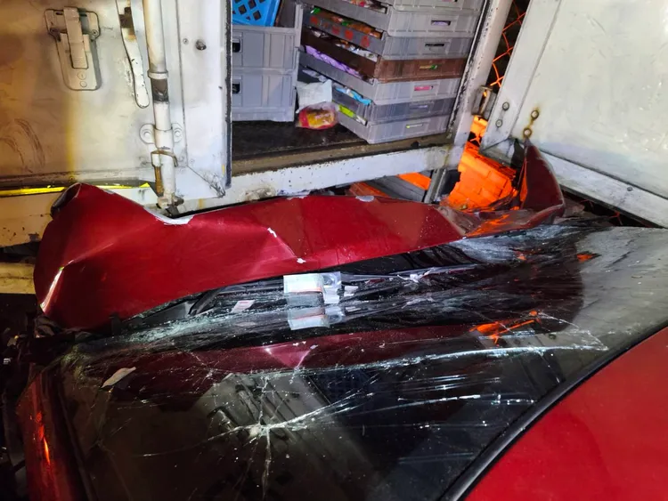 紅色轎車未減速衝入貨車後方底部，現場一片狼藉，可見撞擊力之大。翻攝畫面