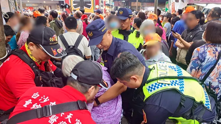 白髮阿嬤排隊鑽轎底，不慎遭人推擠跌倒，臉部掛彩被警方與民眾協力帶到一旁休息包紮，所幸無大礙。翻攝畫面