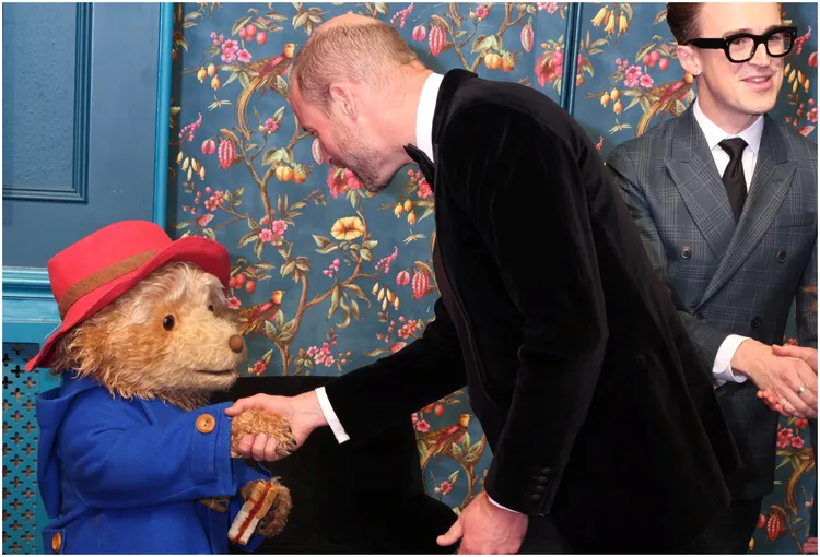 威廉王子（中）与演员扮成的柏灵顿熊握手寒暄。路透