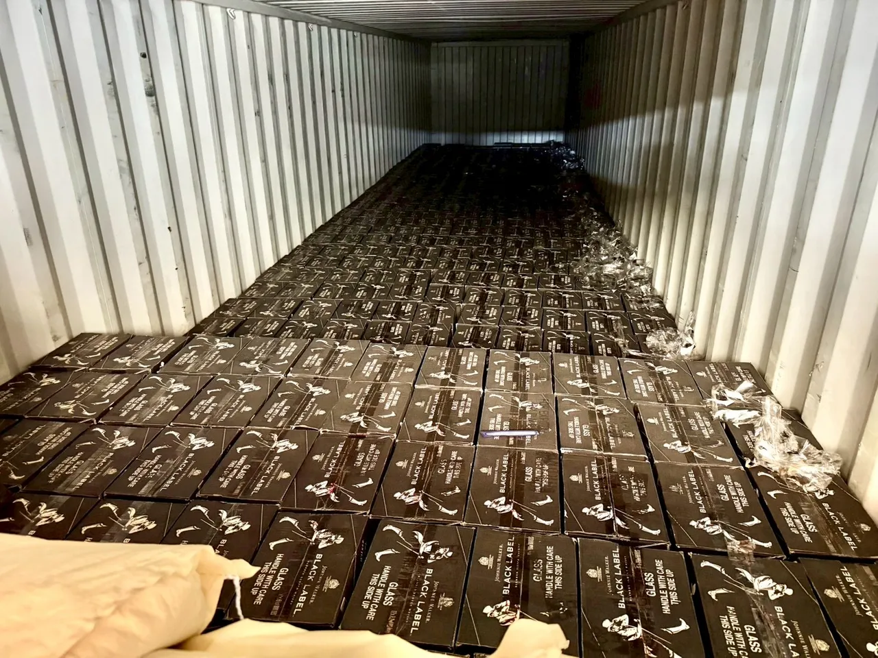 櫃門前兩排處以塑膠粒等貨物掩飾酒品。翻攝畫面