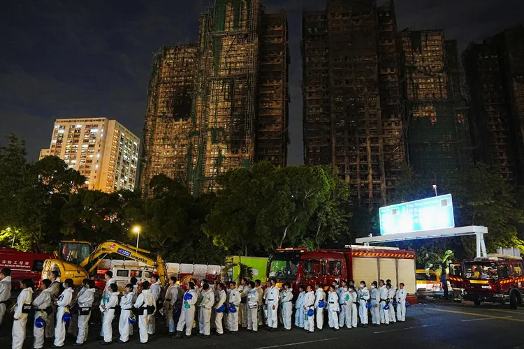 香港警察穿著防护衣进入宏福苑灾后现场寻找失联者。路透