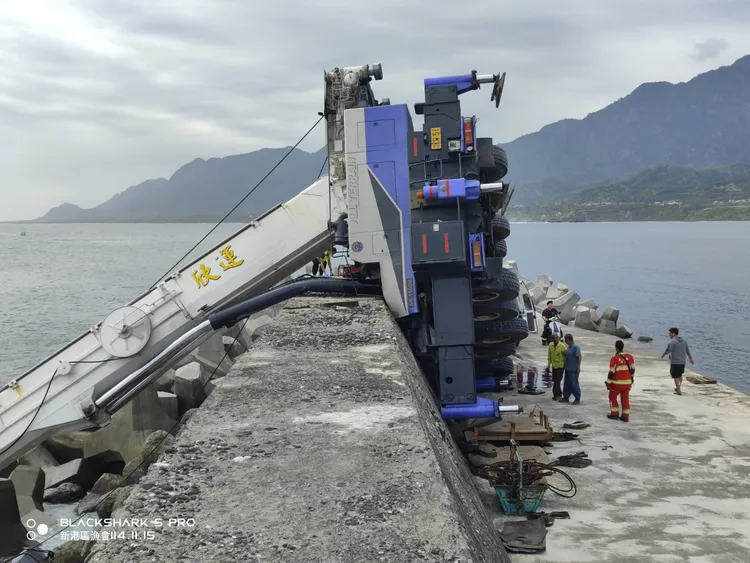 一輛吊車在成功漁港作業時不慎翻覆。民眾提供
