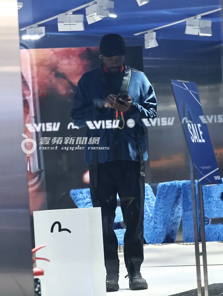 團員will.i.am在服飾店邊滑手機挑選單品。特勤中心攝