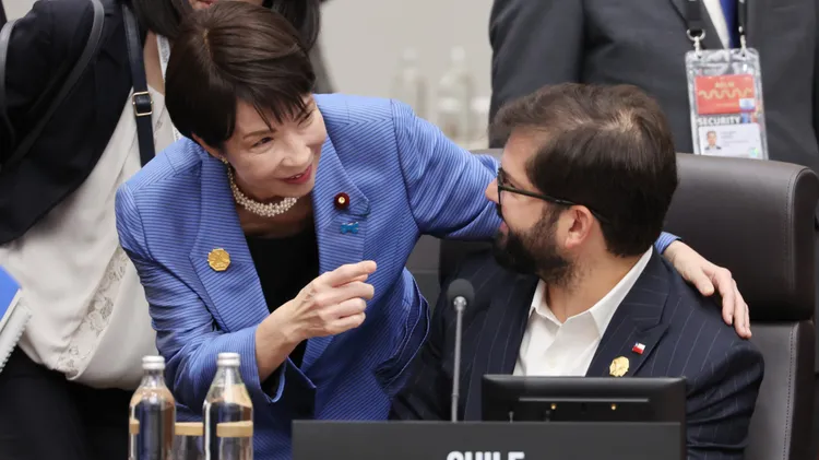 高市早苗（左）搭肩与智利总统波里奇交流。美联社