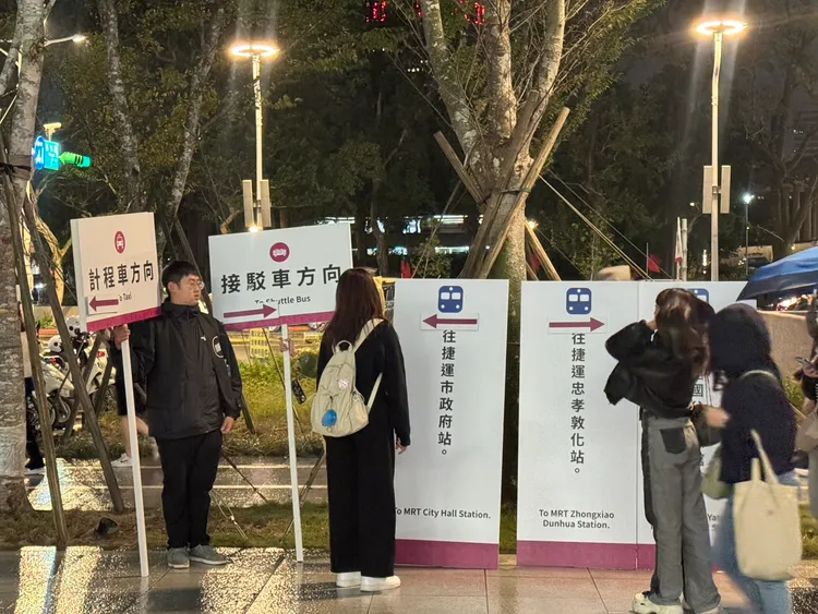 工作人員舉牌指引方向協助疏運。張綵茜攝