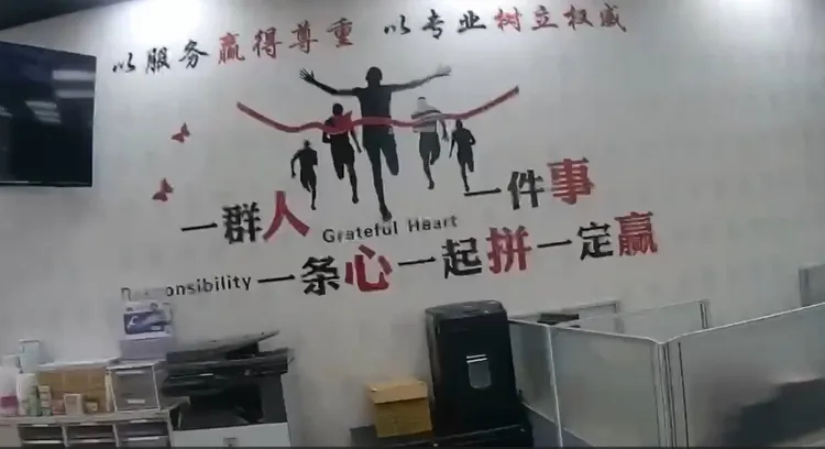 黑幫所操控的承益融資公司內牆上貼著團結標語，用簡體字鼓勵大家要一條心一起拚就一定贏。翻攝畫面