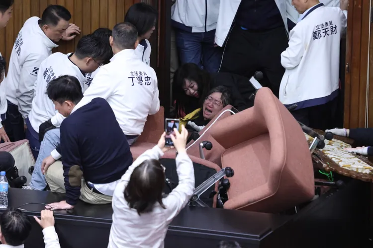 立法院去年12月审理选罢法、宪法诉讼法及财划法等修正草案， 国民党立委将民进党立委陈培瑜架离主席台。彭欣伟摄