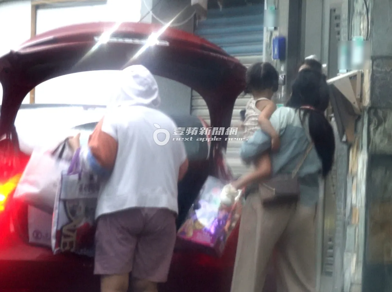 保母抱著小元宝下车，与另一名在家门口等待多时的保母，一起到后车厢搬东西。特勤中心摄