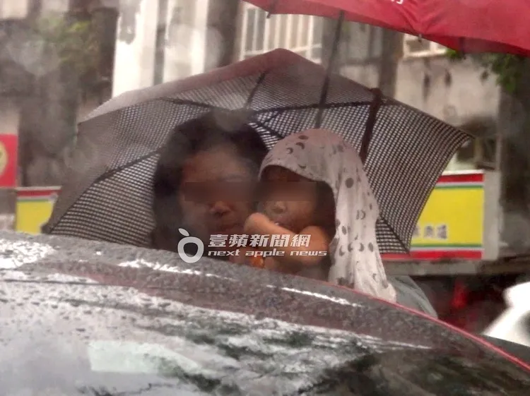小元寶由保母抱上車，一旁友人幫忙撐傘。特勤中心攝