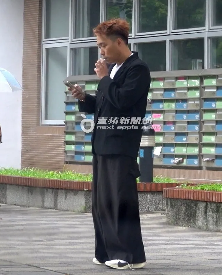 余祥銓抓緊空檔到門口抽加熱菸、滑手機放鬆一下。特勤中心攝