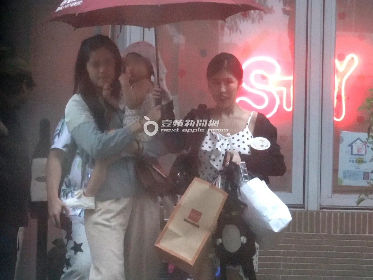 柔柔撑伞和保母在门口等待，女儿「小元宝」在保母怀中。特勤中心摄