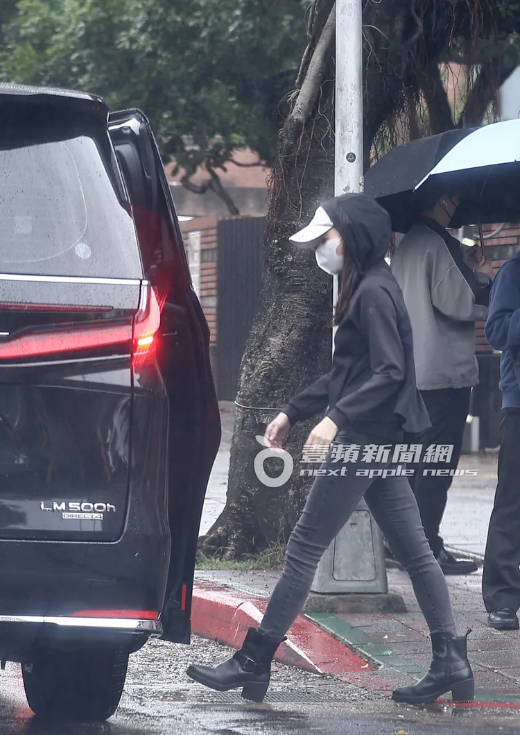 20分鐘後，完成任務的曾馨瑩拉起外套帽子遮雨，上車離開。特勤中心攝