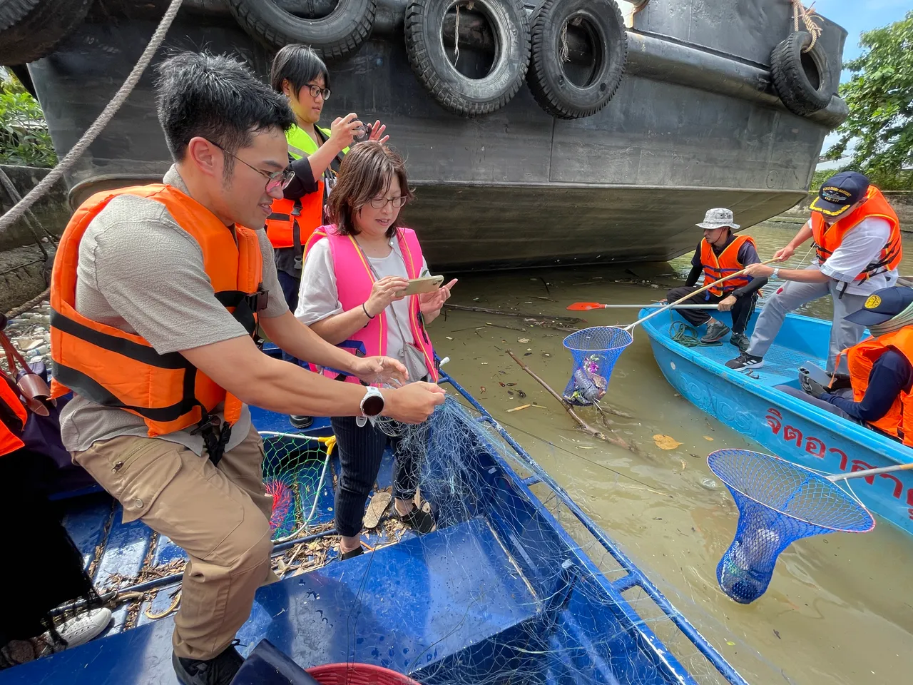 与会专家登上小船捞拾河面漂浮垃圾。海委会提供