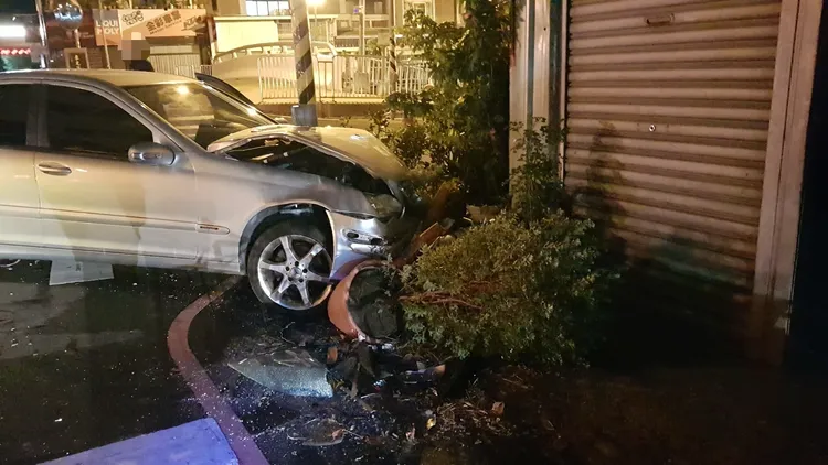 賓士車與休旅車碰撞，失控後衝向路旁，還撞破民宅前花盆，最後卡在號誌桿上。翻攝照片