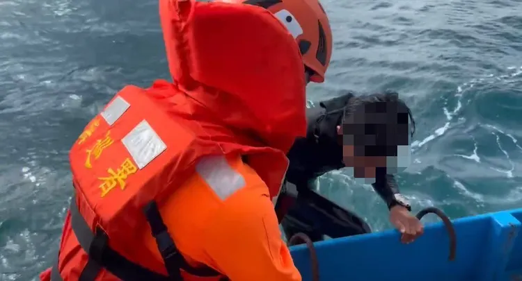 海巡人員請附近作業漁船協助救起衝浪客。岸巡13大隊提供