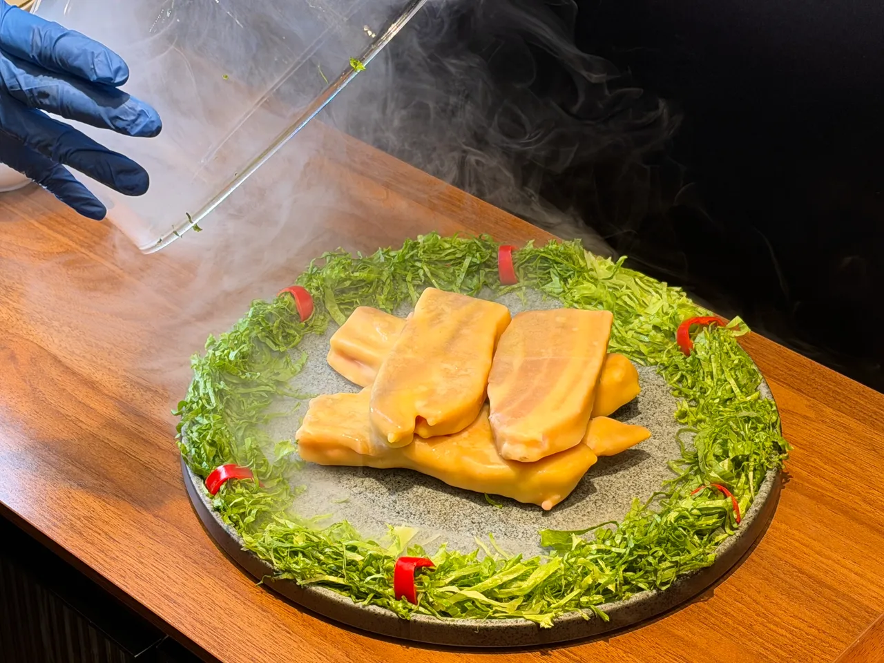 「黄金蜂蜡熟成黑猪肉」以透明烟熏罩上桌，开启时弥漫熟成香气。庄伟祺摄